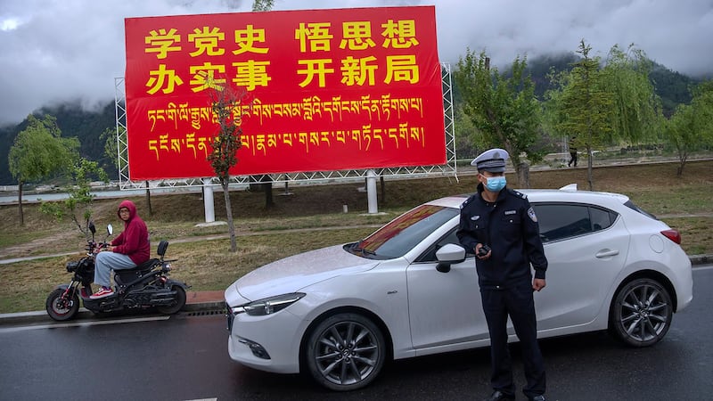 资料图片:2021年6月4日,一名警察在西藏自治区林芝市的一个广告牌附近。 (美联社)